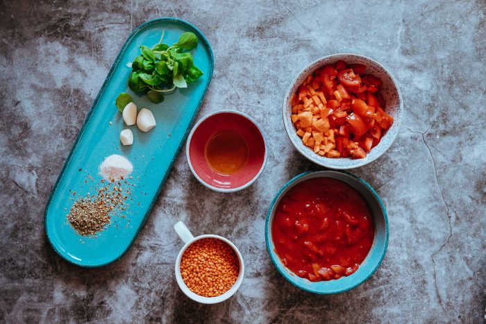 Ingredience na omáčku z červené čočky - budete potřebovat červenou čočku, česnek, mrkev, rajčata, rajčatový protlak a koření.