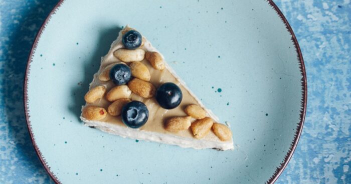 Nepečený cheesecake ozdobte ovocem a arašídy.